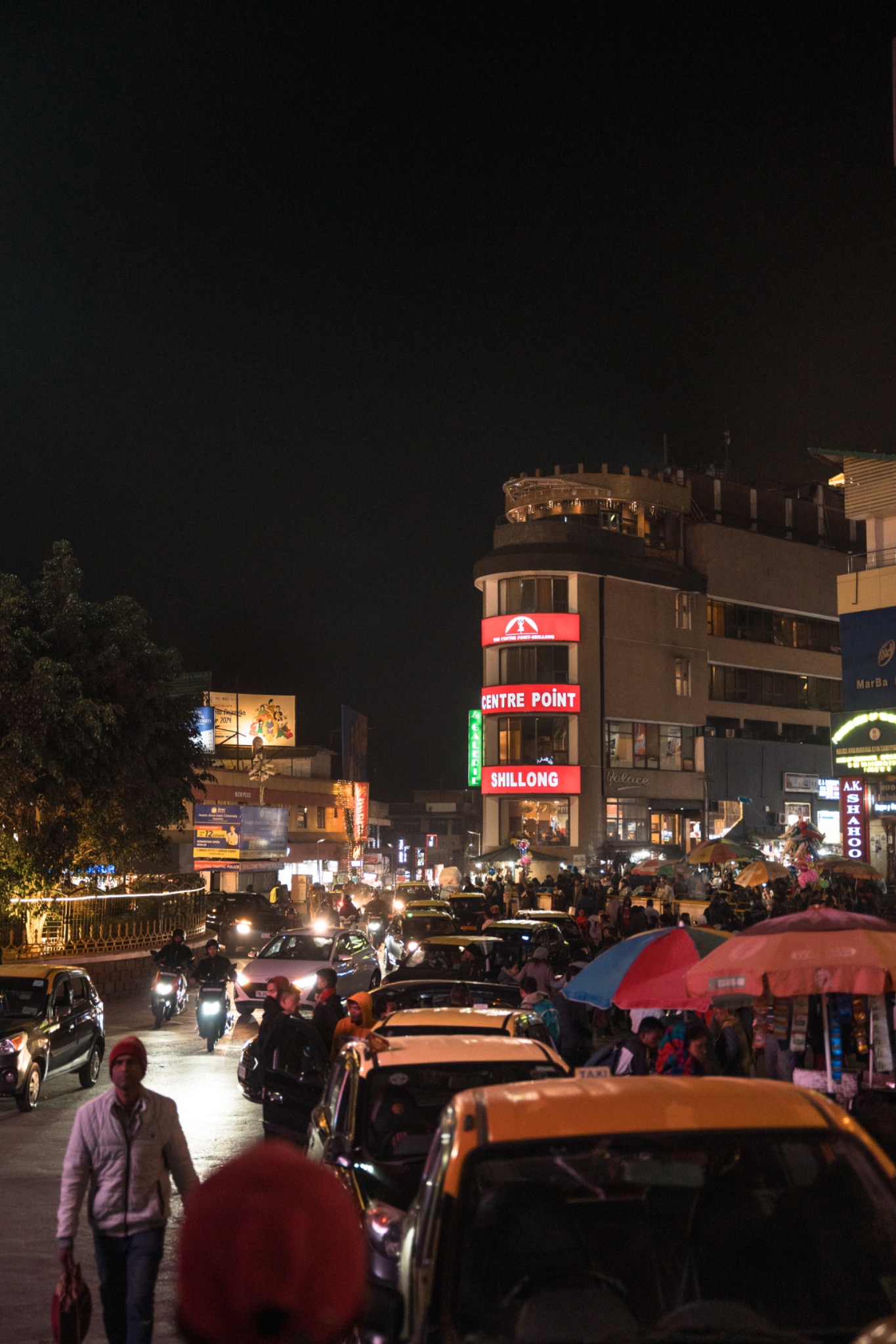 People and cars moving through a busy city street at night