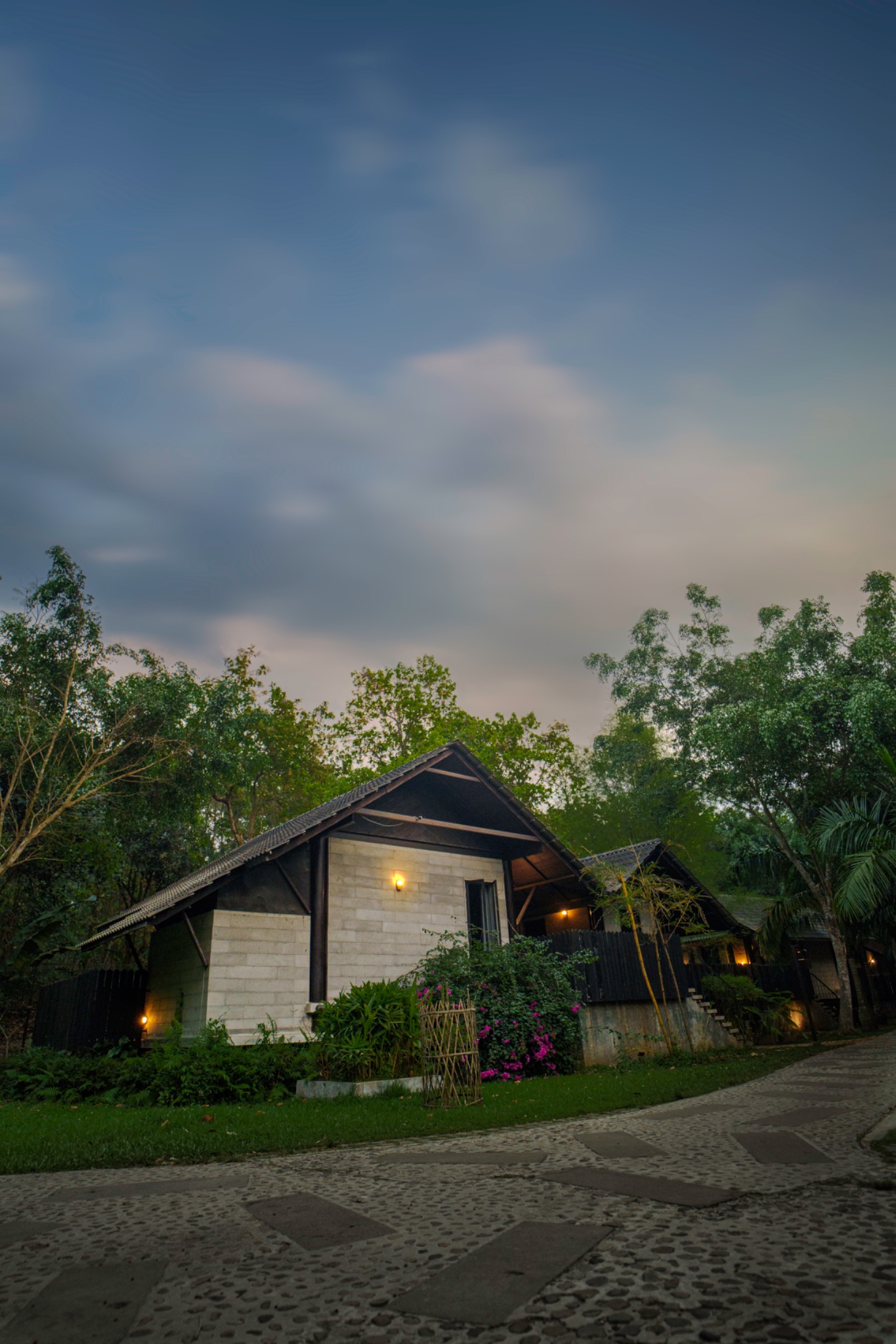 A small cottage surrounded by green trees and a garden