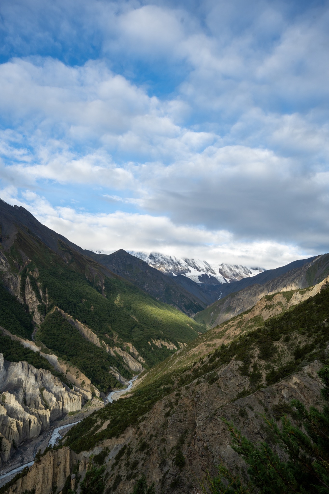A river cutting through a green mountain gorge beneath broken clouds