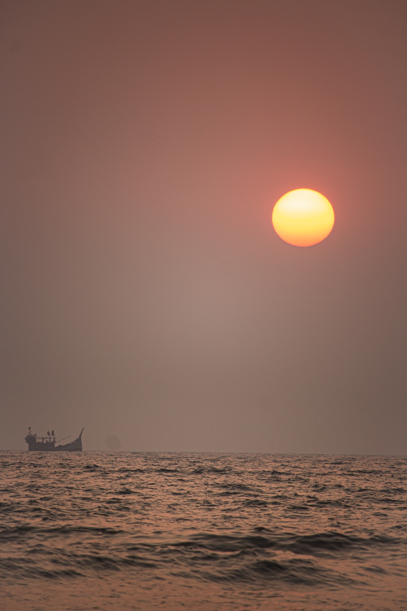 A round orange sun hanging above a muted sea