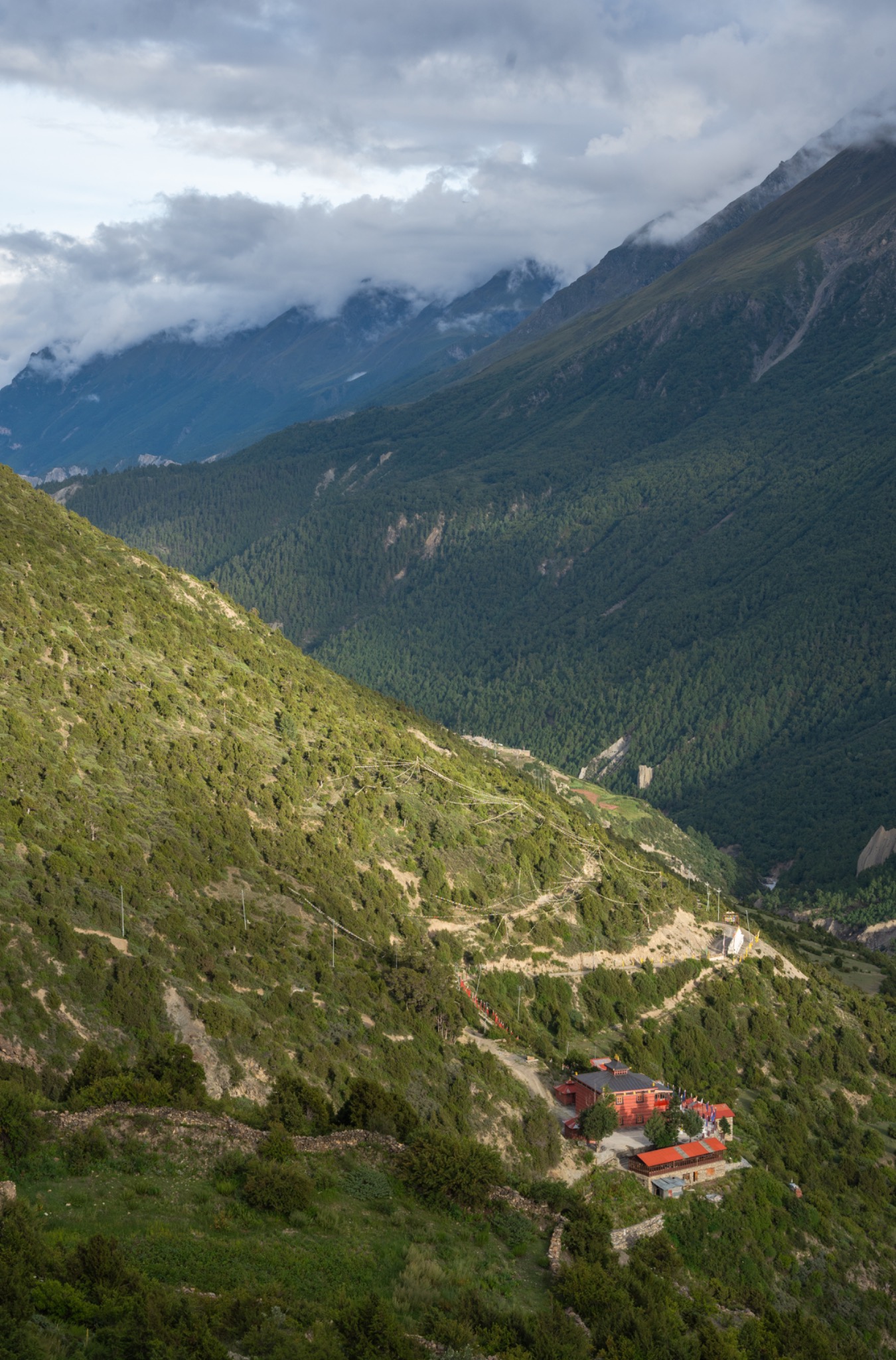 A red-roofed lodge far below on a green mountain trail