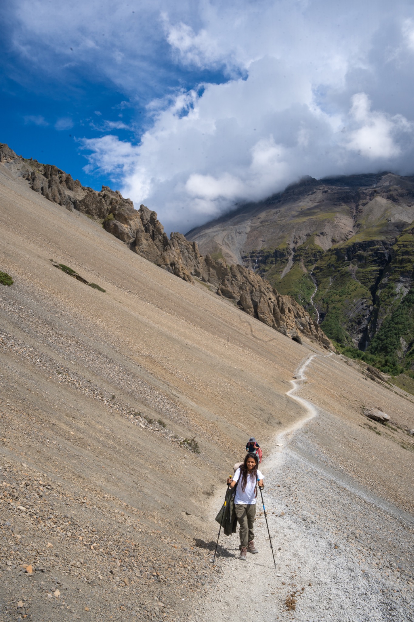 Hikers climbing a zigzag path across a steep rocky slope